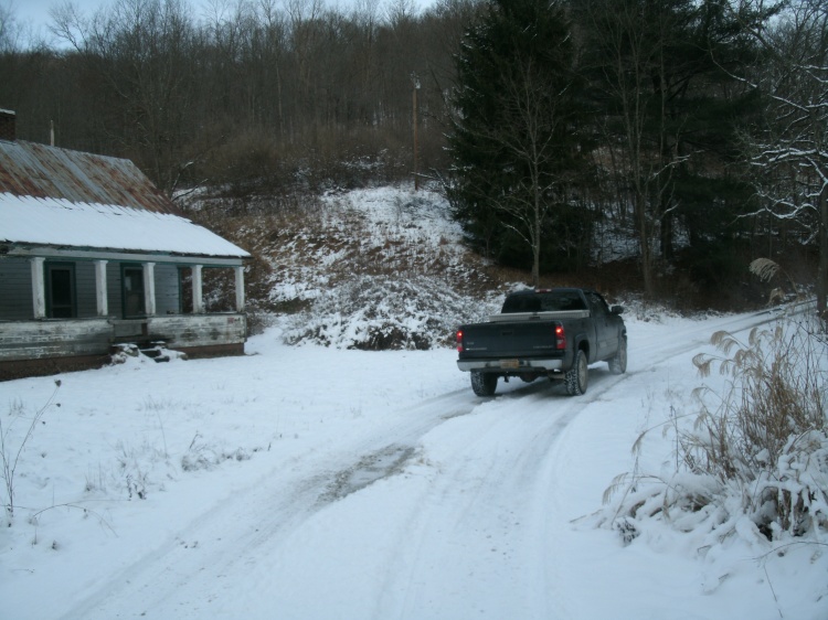 toms truck on a snowy road near old house